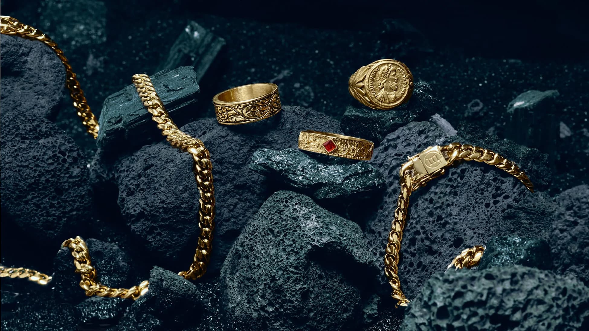 Marcozo premium jewelry hero with gold pieces arranged on dark volcanic stone